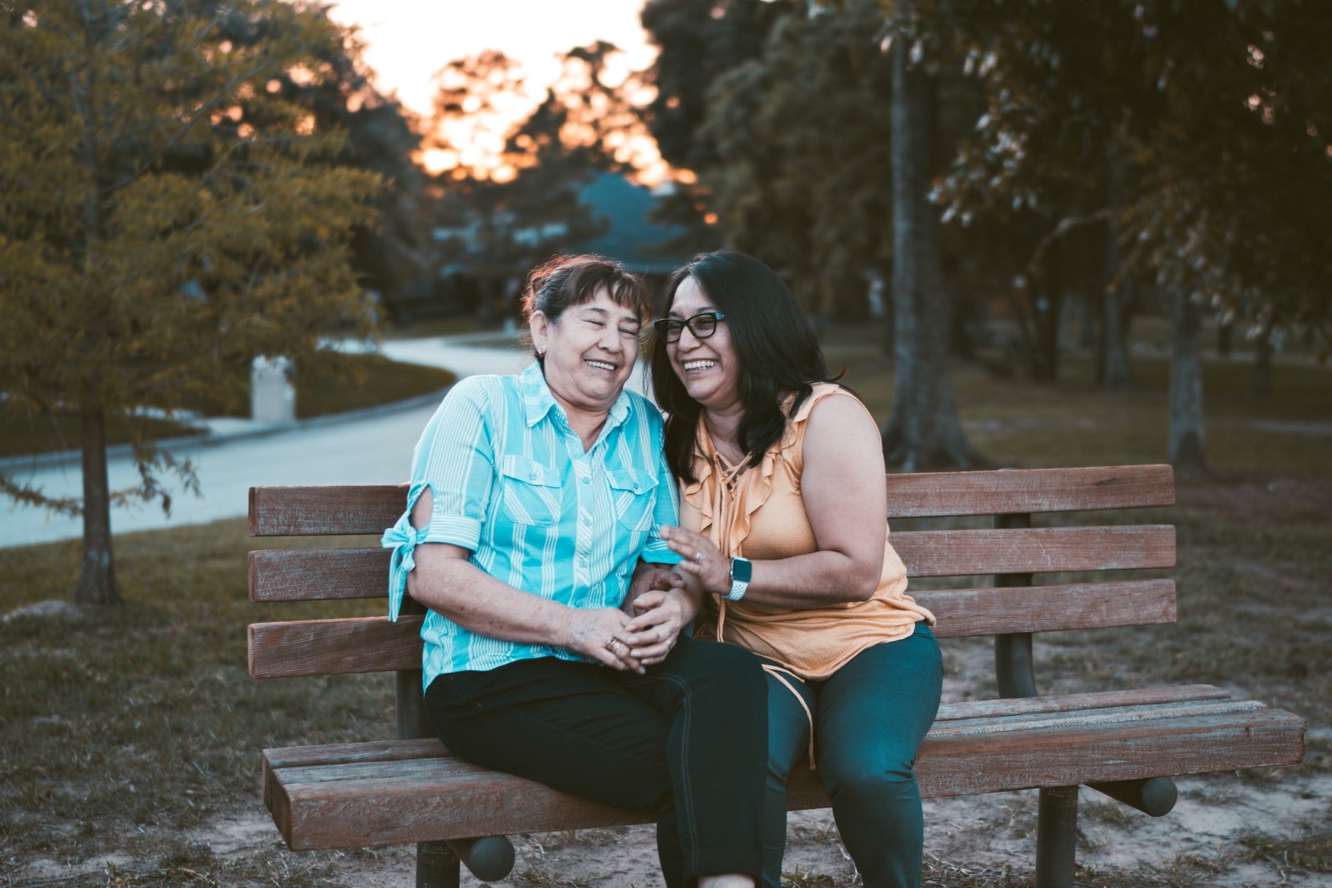 Two adults sitting on a bench together, laughing.