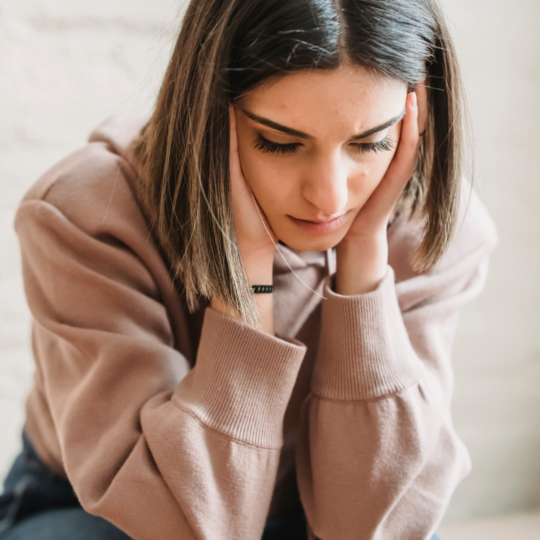 A worried woman with her hands on her face.